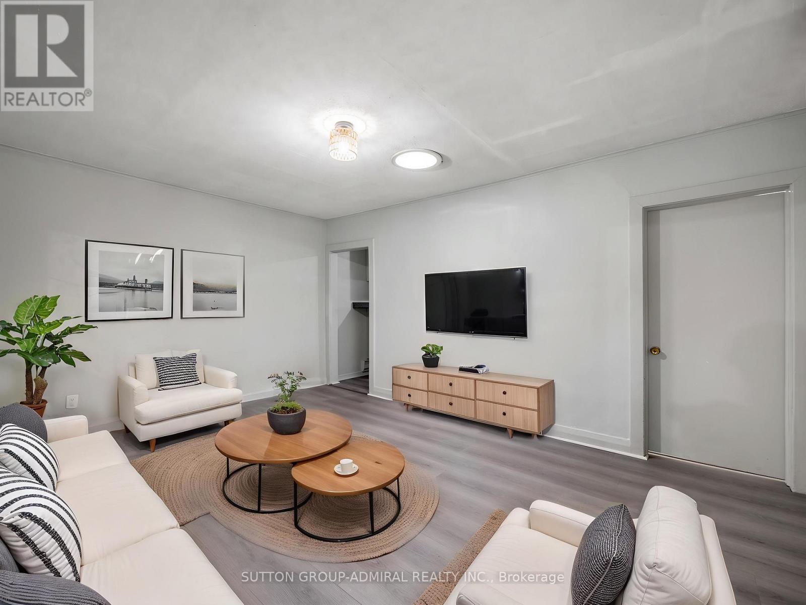 A living room with a white couch, a coffee table, and a flat-screen TV.