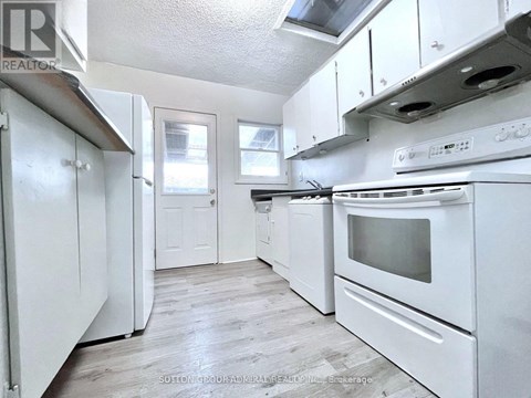 A white kitchen with a stove top oven and a refrigerator.