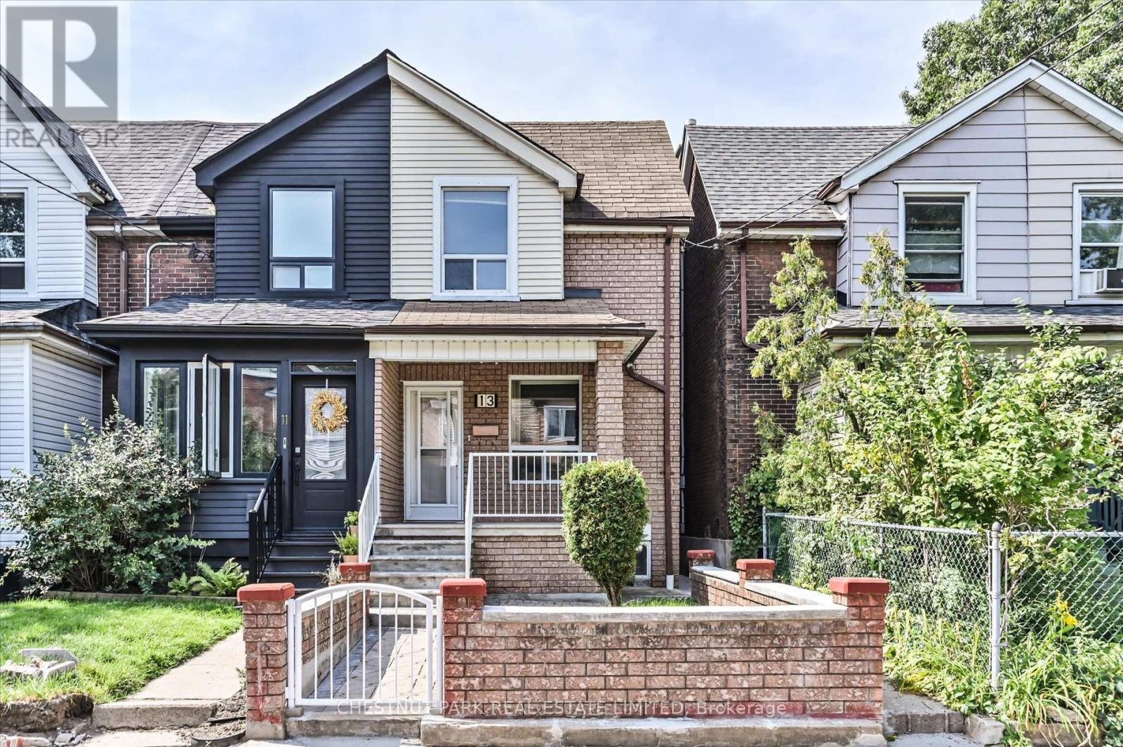 A house with a black front door and a brick wall in front.