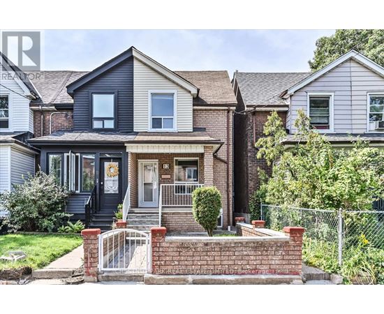 A house with a black front door and a brick wall in front.