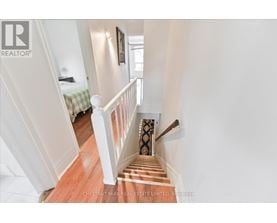A staircase with a wooden floor and white railings leads to a bedroom.