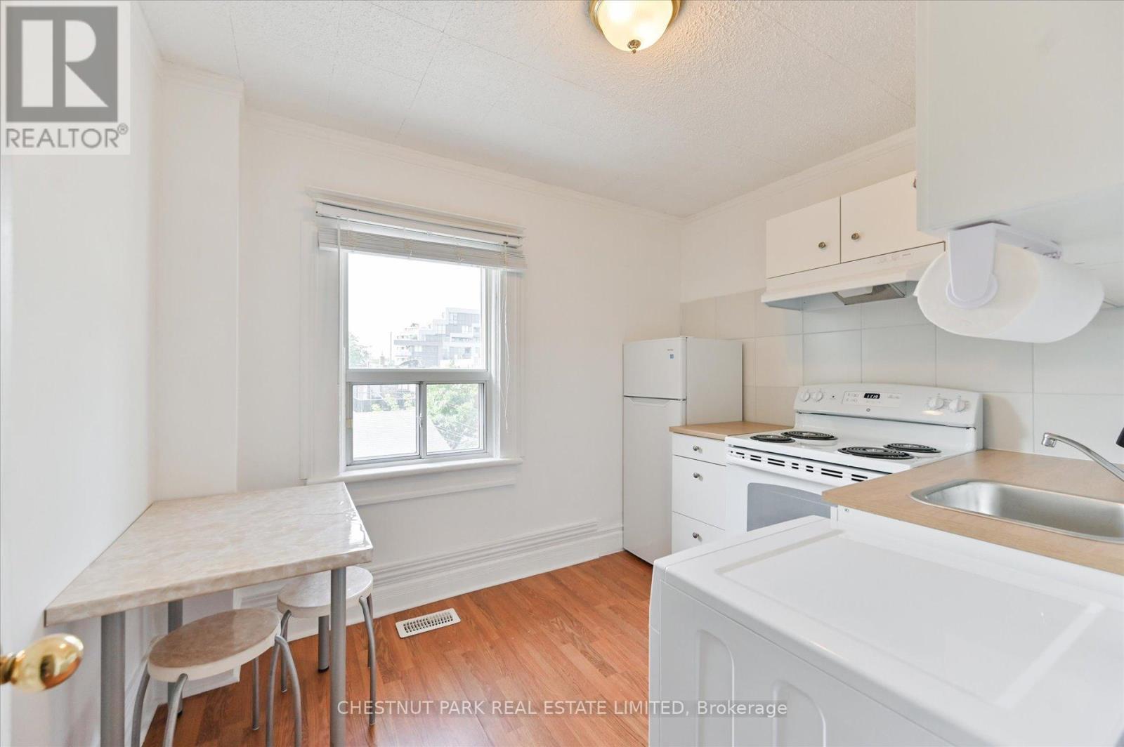 A small white kitchen with a table and chairs.
