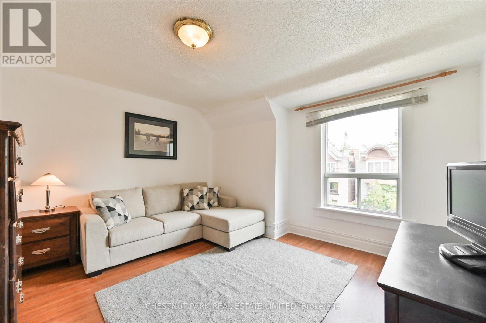 A living room with a white couch and a grey rug.