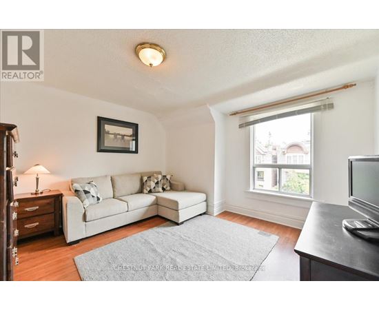 A living room with a white couch and a grey rug.