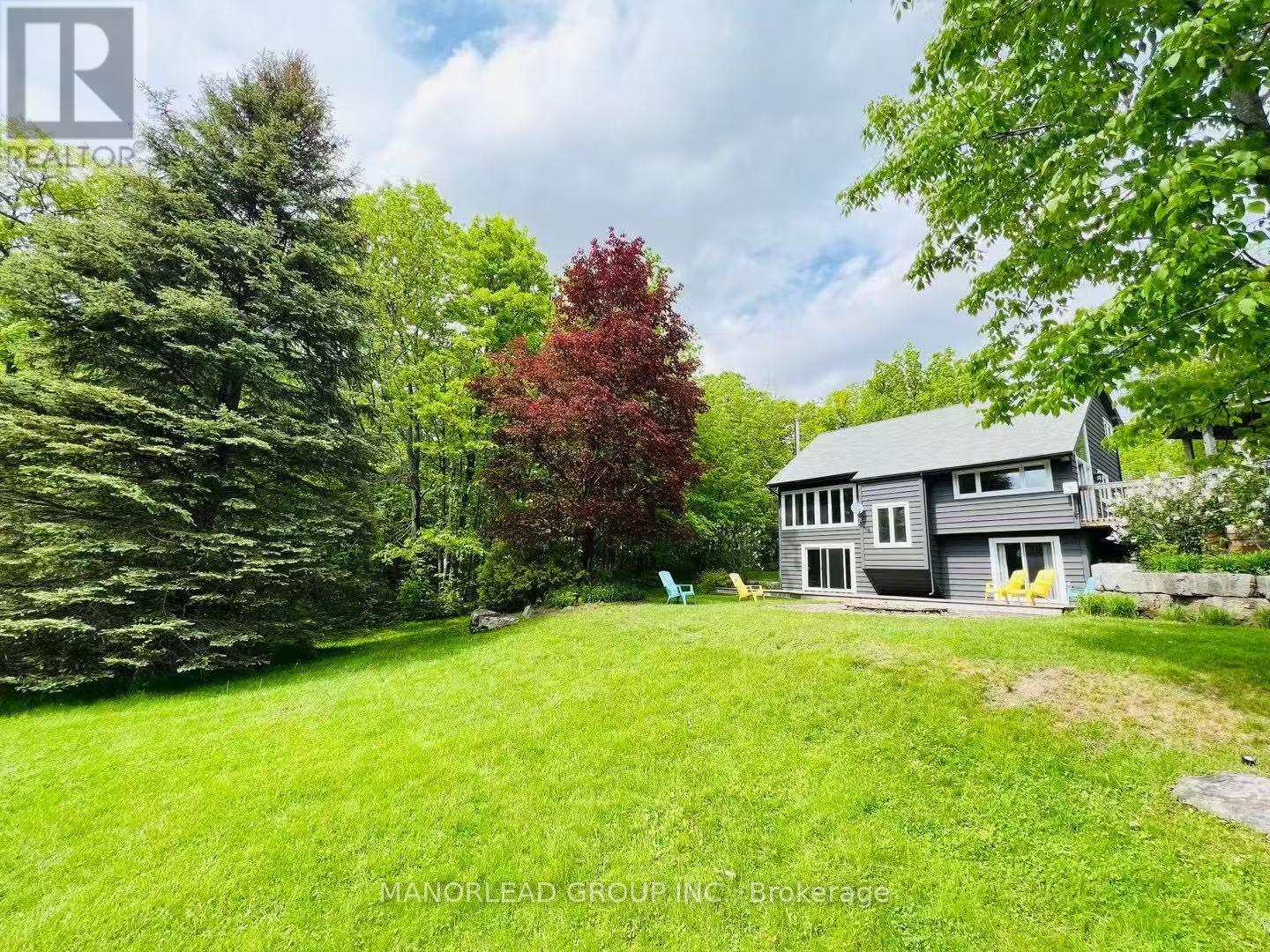 A house with a grey roof and a green lawn in front of it.