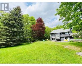 A house with a grey roof and a green lawn in front of it.