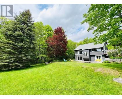 A house with a grey roof and a green lawn in front of it.
