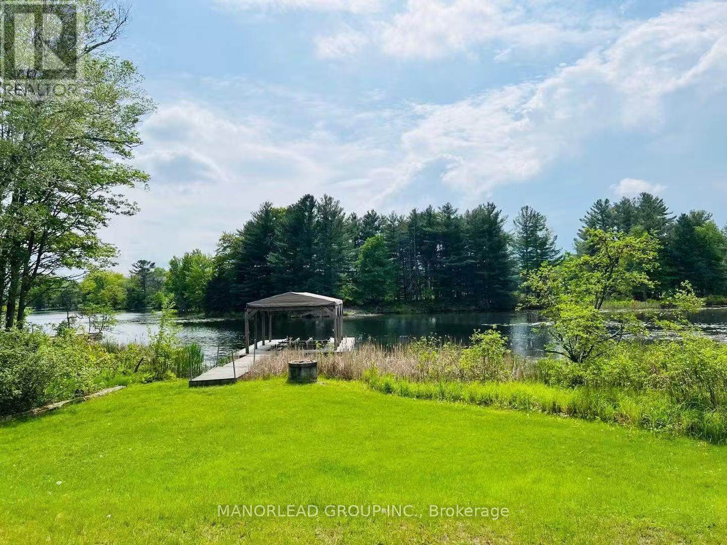 A gazebo sits on a grassy area by a lake.