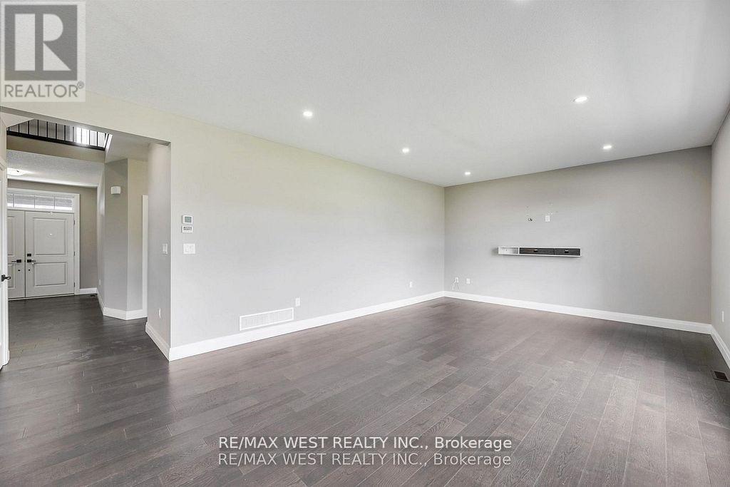 A spacious room with wooden flooring and white walls, brokerage by RE/MAX West Realty Inc.
