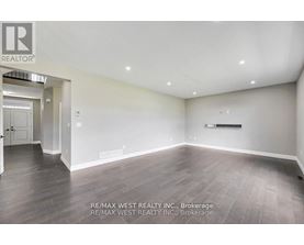 A spacious room with wooden flooring and white walls, brokerage by RE/MAX West Realty Inc.