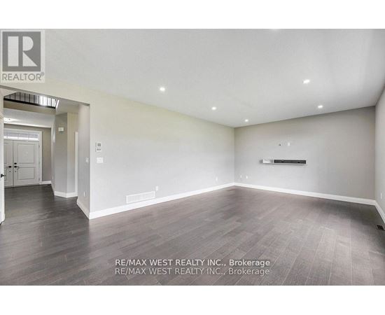 A spacious room with wooden flooring and white walls, brokerage by RE/MAX West Realty Inc.