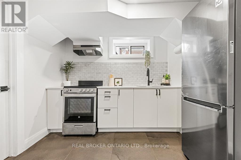 A modern kitchen with a stainless steel refrigerator and a brick backsplash.