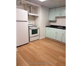 A kitchen with white appliances and wooden floors.