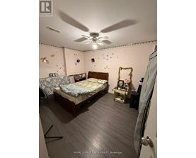 A bedroom with a bed, a fan, and a dresser.
