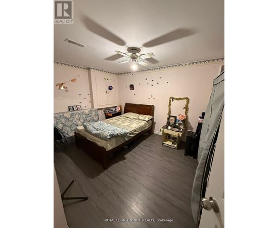 A bedroom with a bed, a fan, and a dresser.