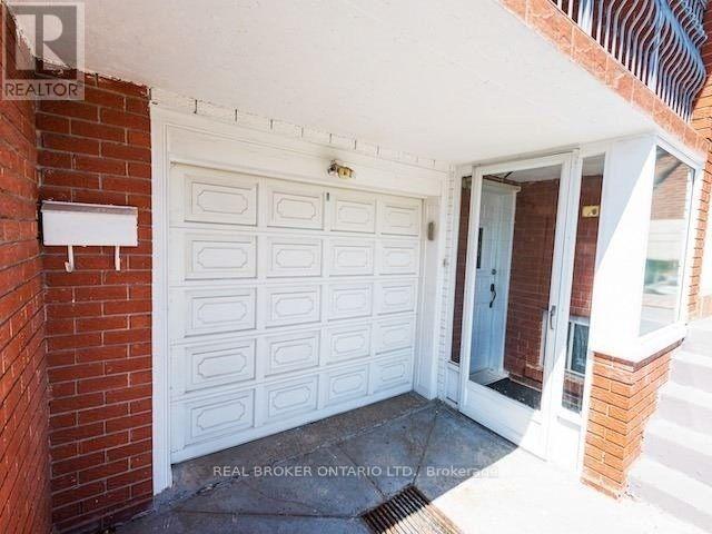 A white garage door is on the left side of a brick wall.