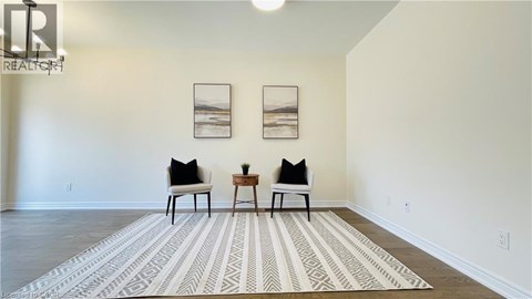 A living room with a rug, two chairs and two pictures on the wall.