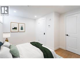 A bedroom with a bed, two pictures on the wall, and a lamp on the side table.