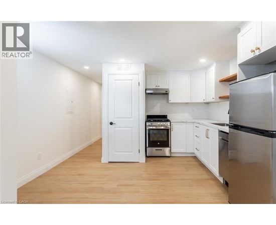 A kitchen with white cabinets and a black refrigerator.