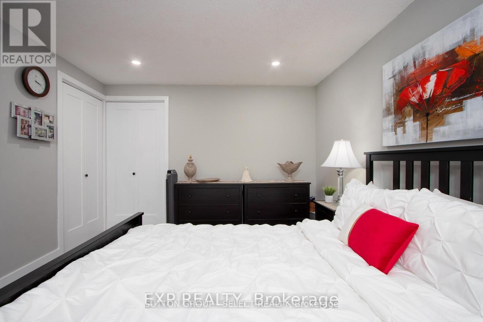 A bedroom with a white bed and a red pillow.