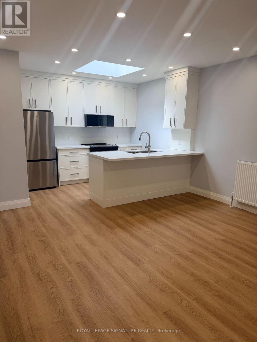 A kitchen with wooden floors and white cabinets.