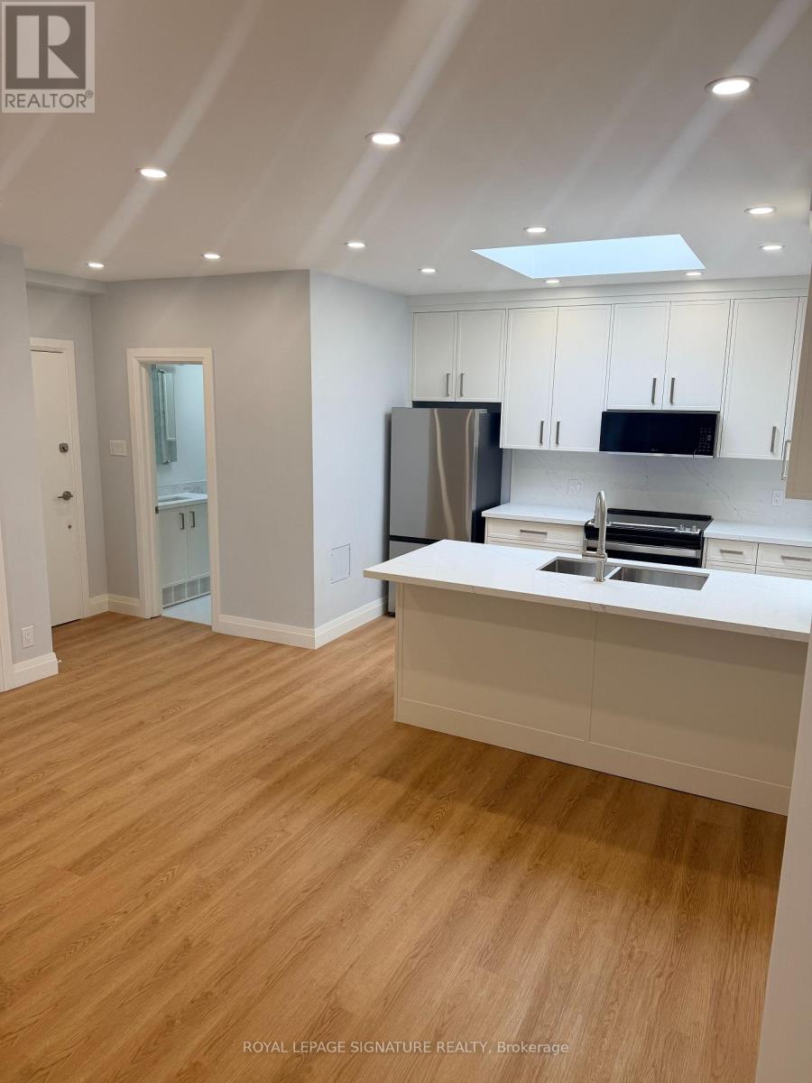 A kitchen with white cabinets and a wooden floor.