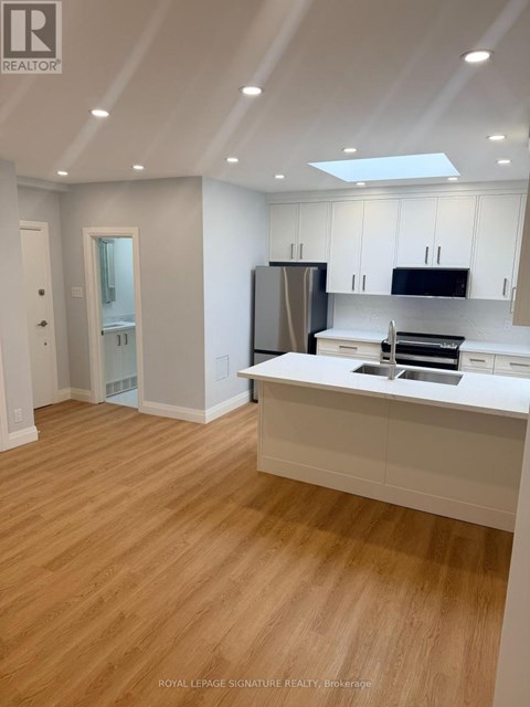 A kitchen with white cabinets and a wooden floor.