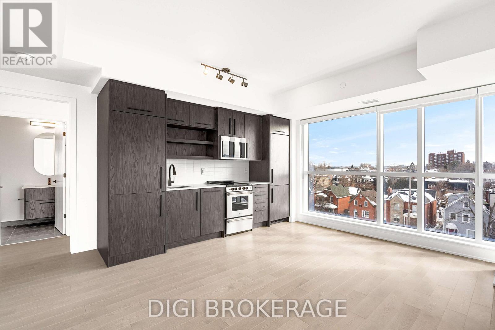 A modern kitchen with dark wood cabinets and a view of the city.