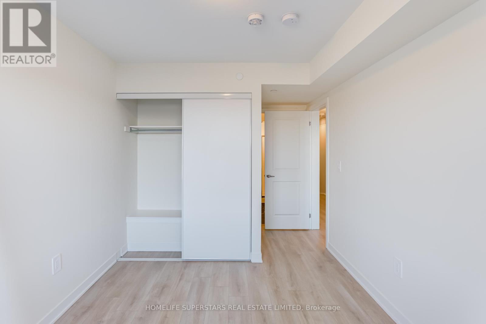 A white bedroom with a sliding door and wooden floors.
