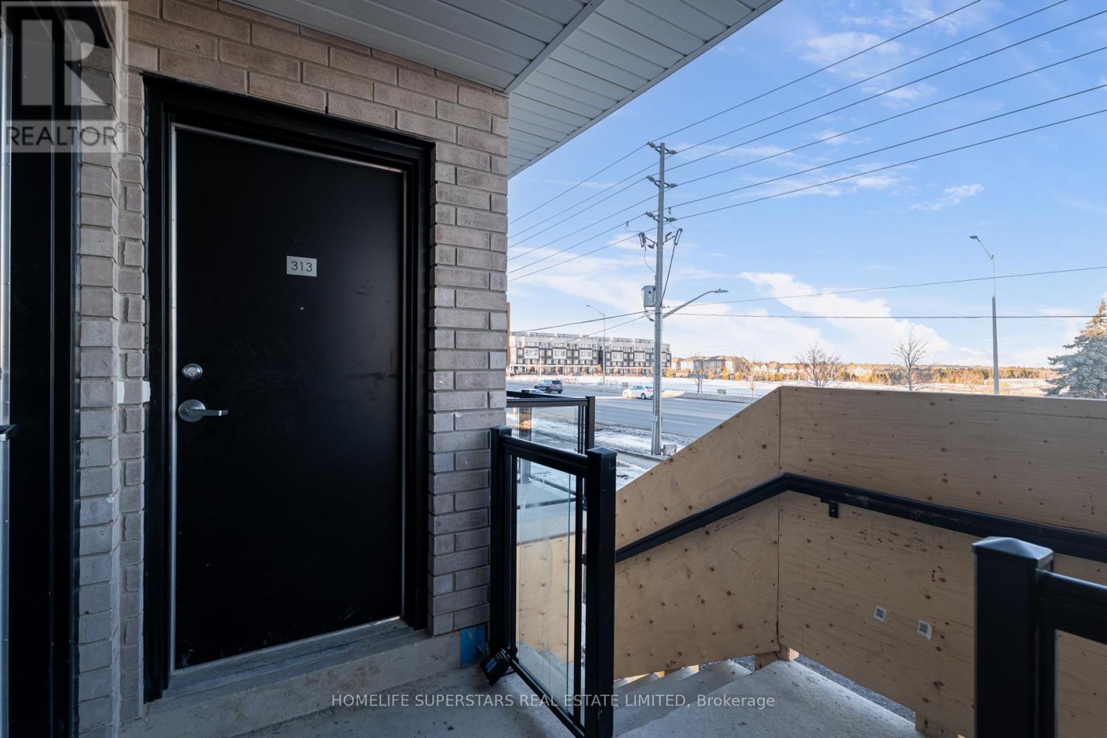 A black door is on the left side of a balcony with a wooden railing.