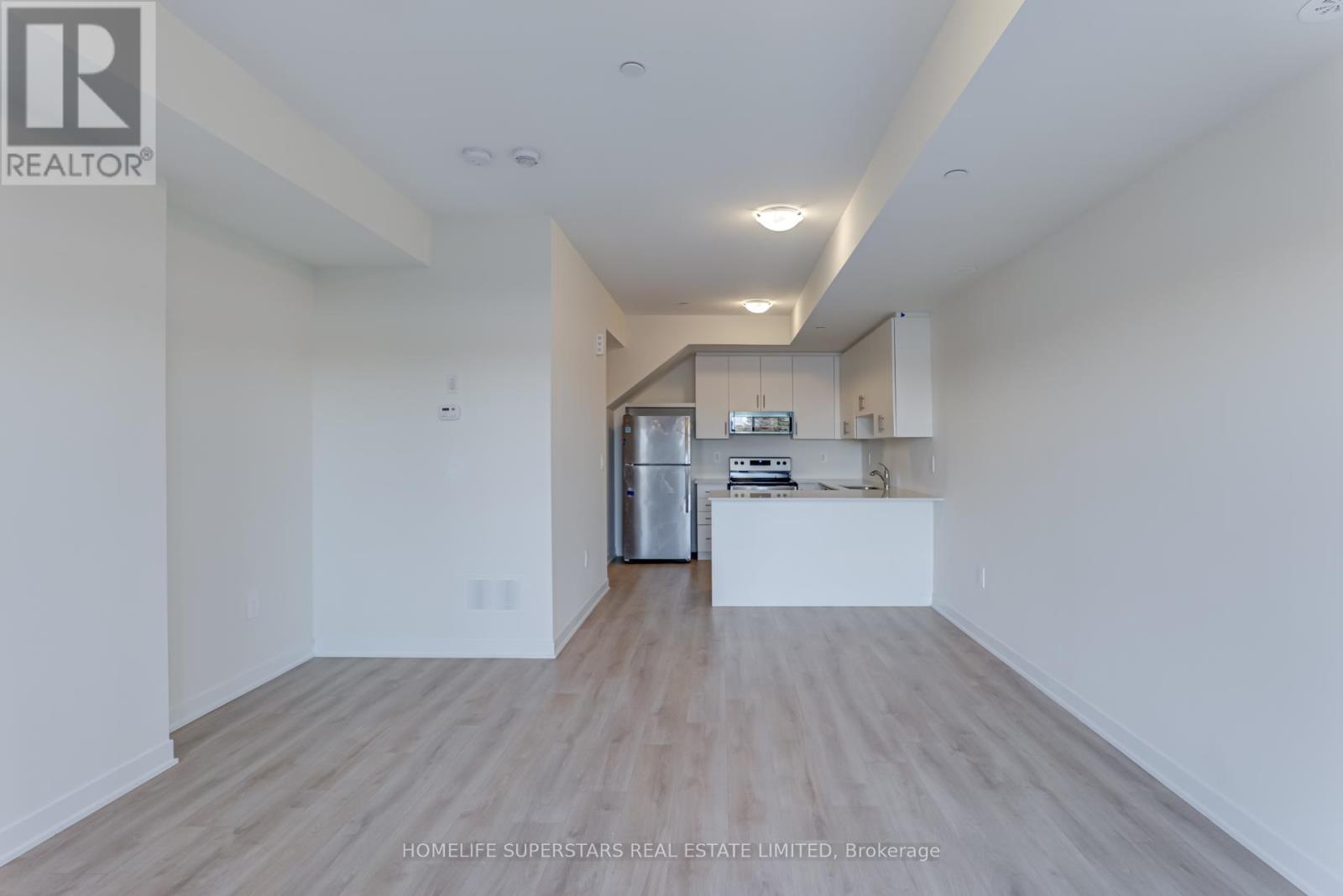 A spacious, empty room with wooden flooring and white walls.