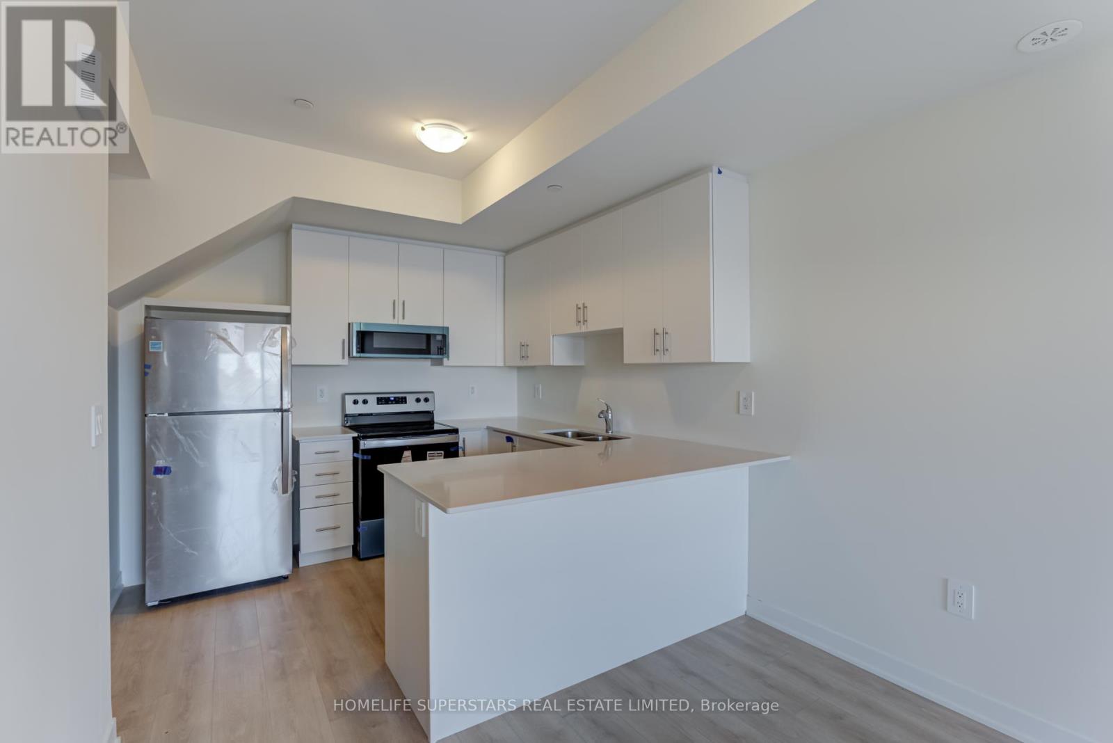 A kitchen with white cabinets and a stainless steel refrigerator.