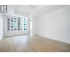 A spacious room with a large window and wooden flooring.