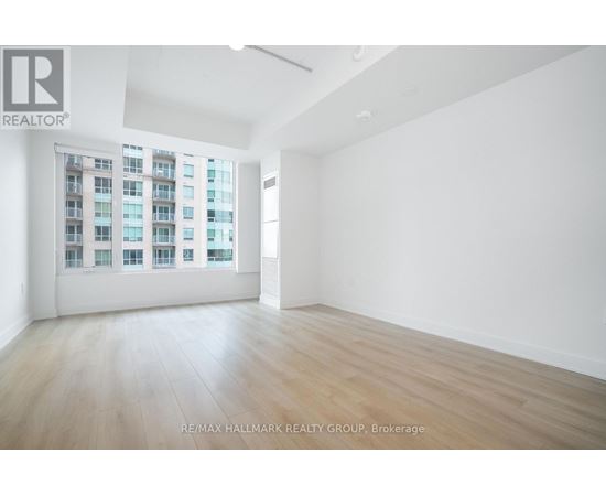A spacious room with a large window and wooden flooring.