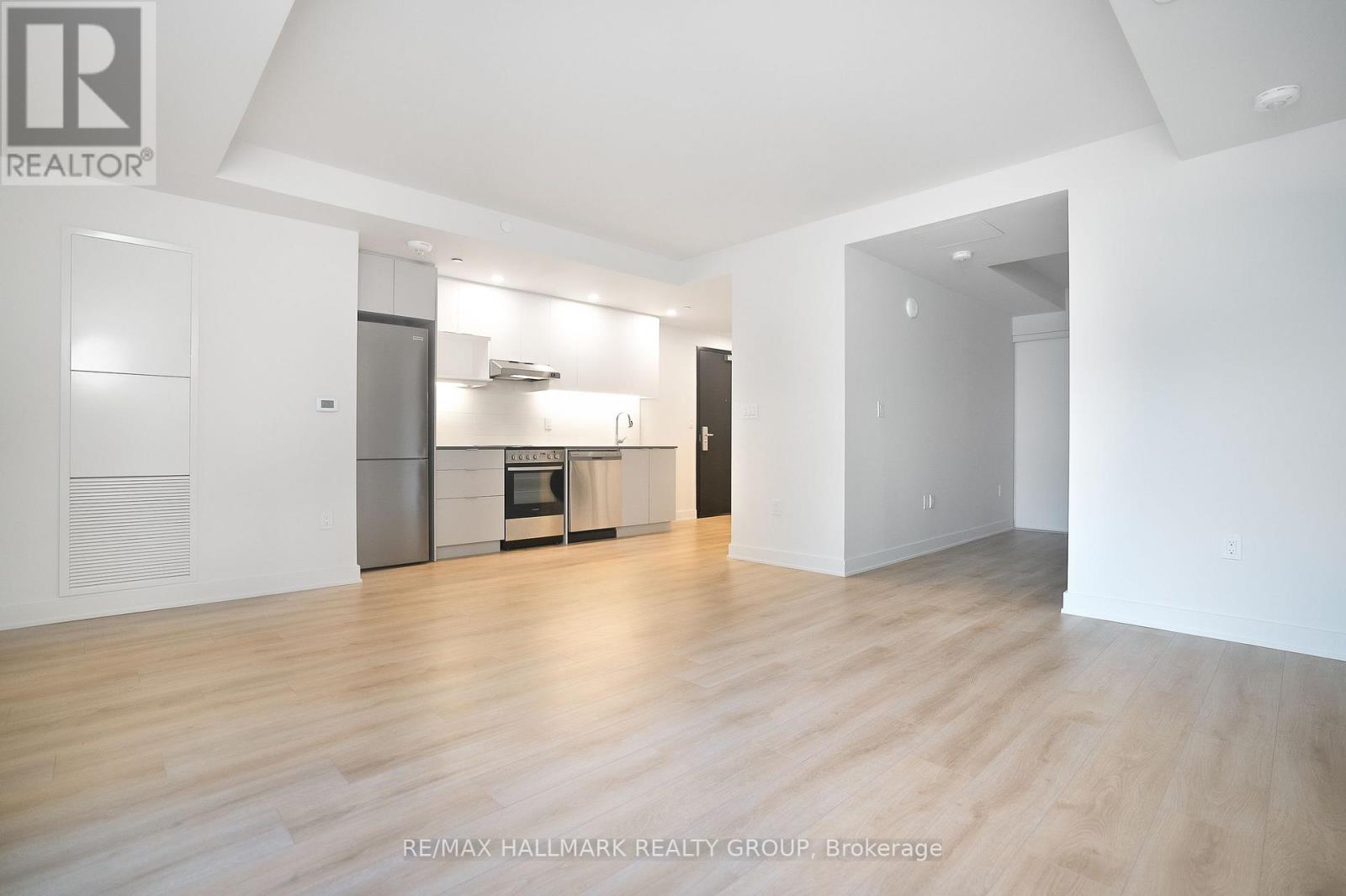 A spacious, empty room with wooden floors and white walls.