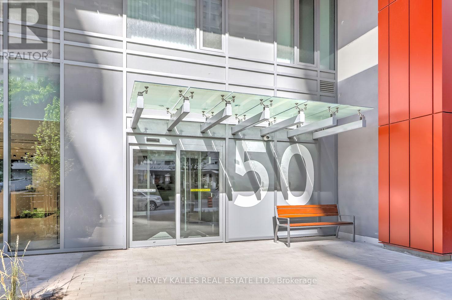 The image shows the front of a real estate office with a glass door and a bench outside.