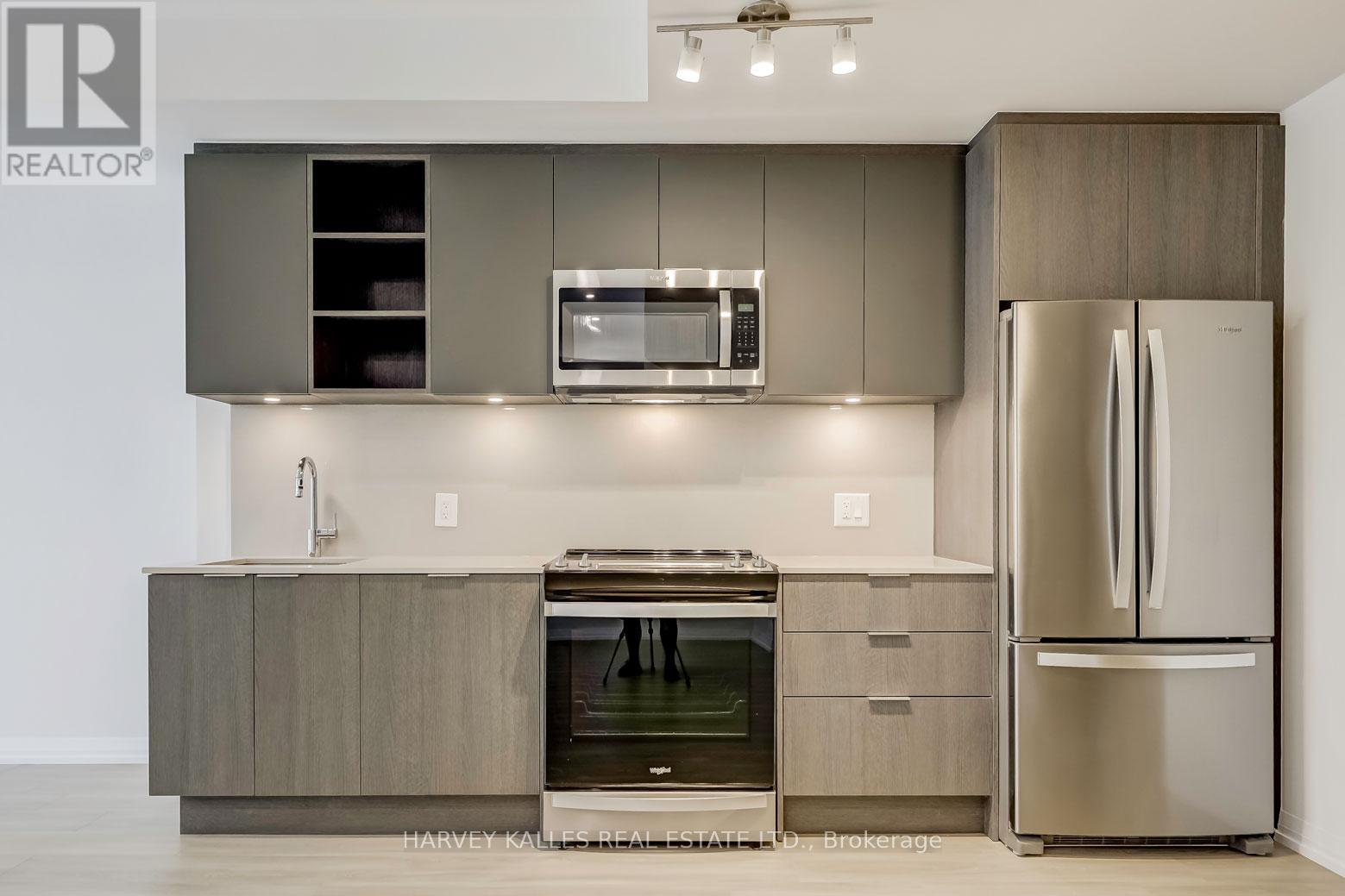 A modern kitchen with a stainless steel refrigerator and a microwave above the stove.