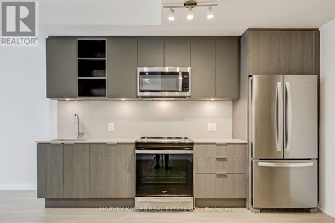 A modern kitchen with a stainless steel refrigerator and a microwave above the stove.