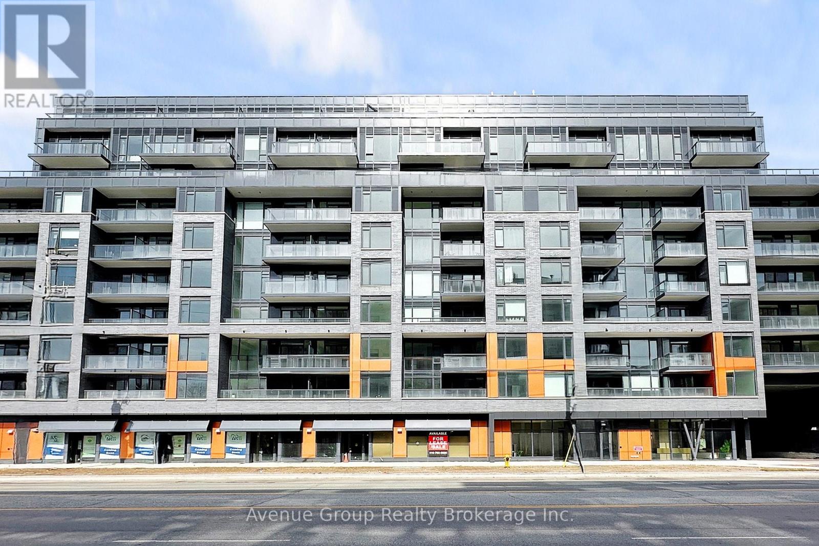 A large apartment building with multiple balconies and orange accents on the ground floor.