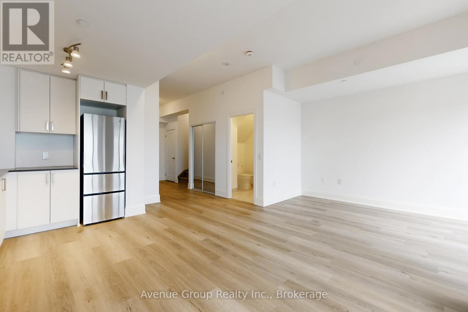 A spacious room with wooden flooring and white walls.