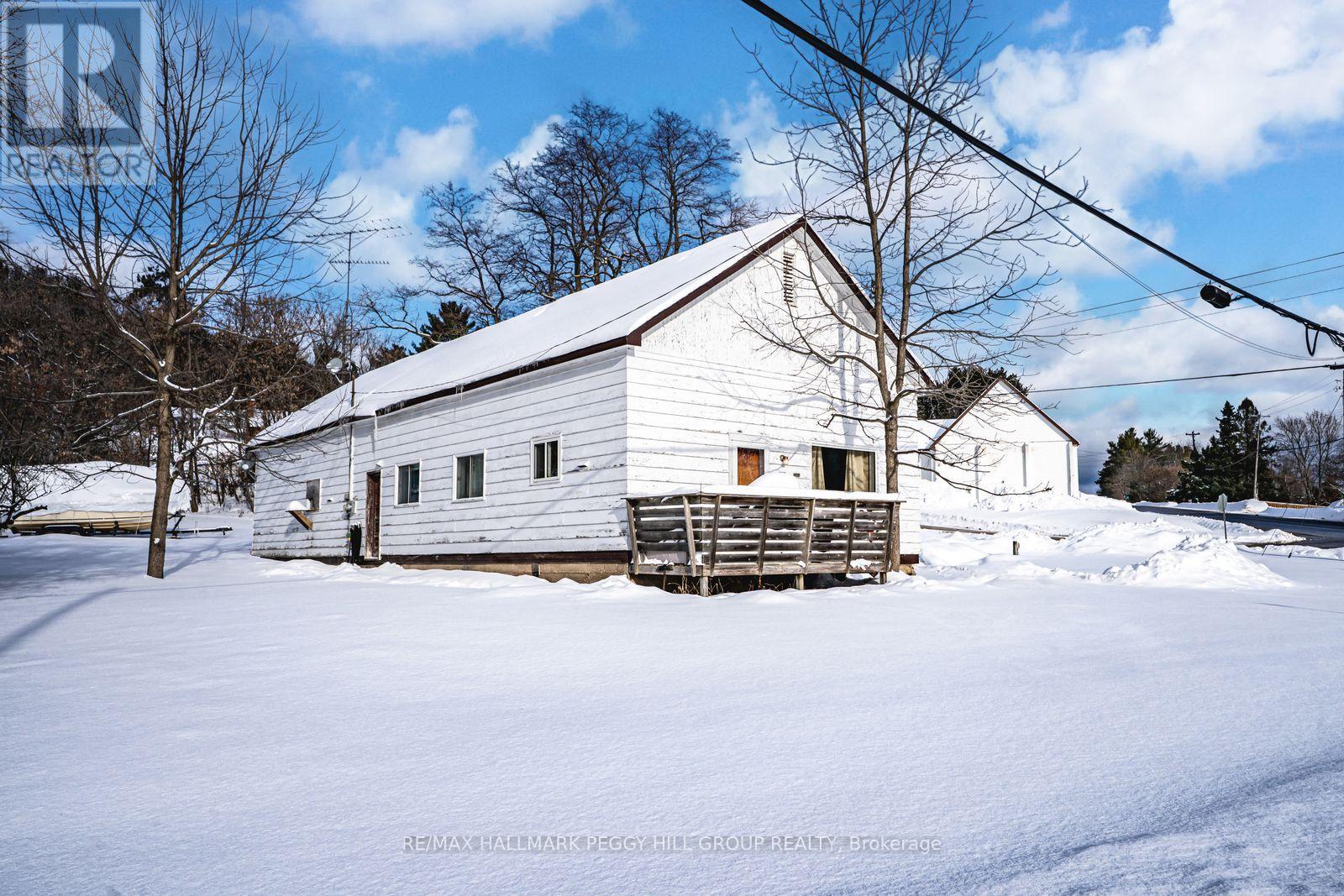 A white barn sits in the snow with a blue sky in the background.