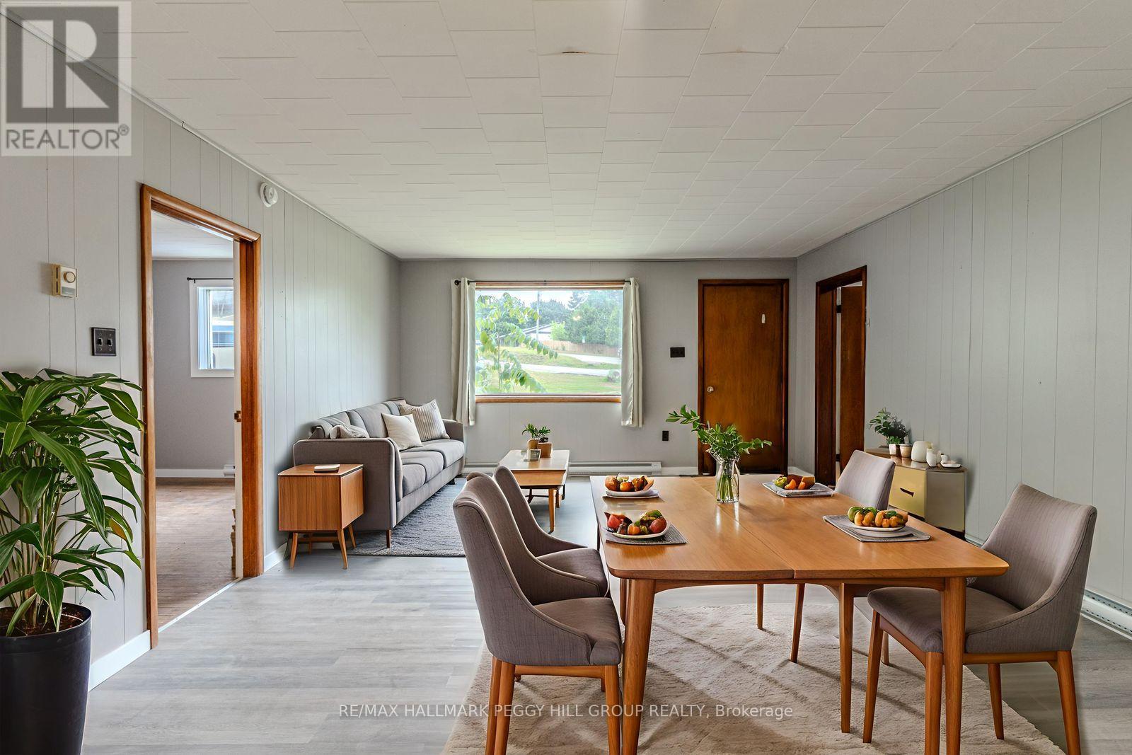 A dining room with a table set for six with a view of a green landscape outside the window.