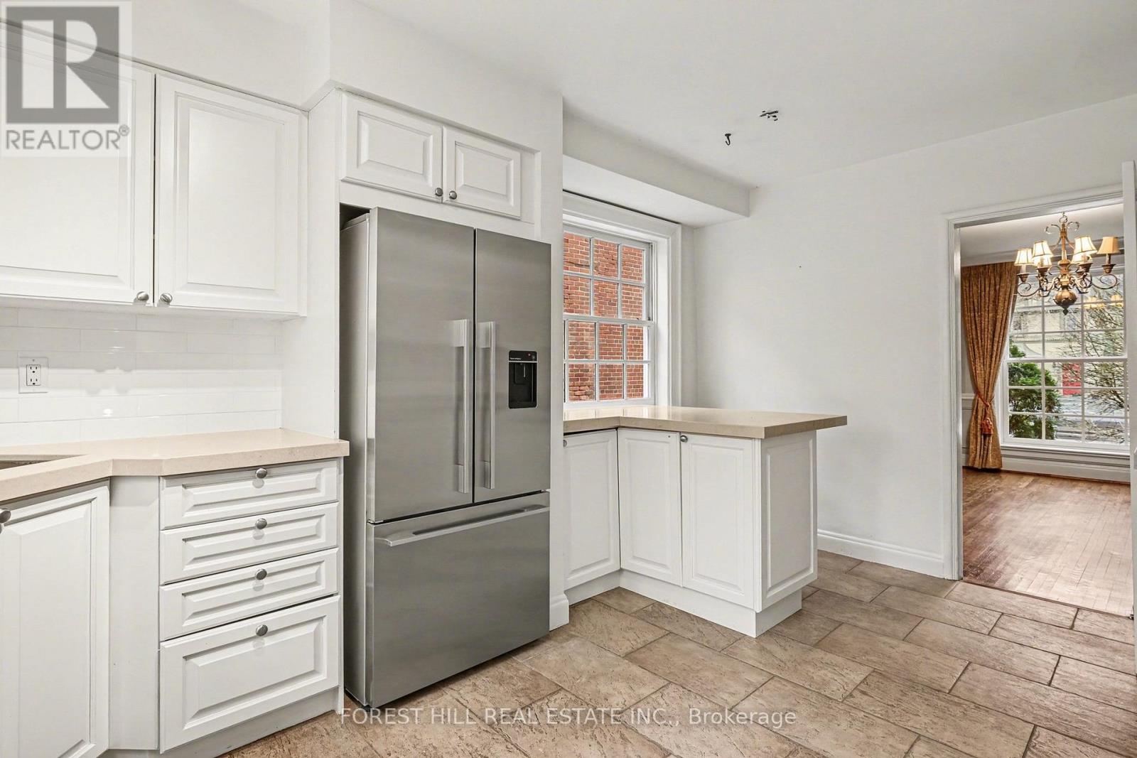 A kitchen with white cabinets and a stainless steel refrigerator.