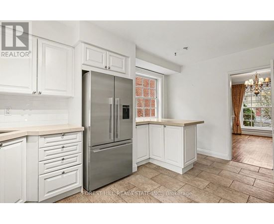 A kitchen with white cabinets and a stainless steel refrigerator.