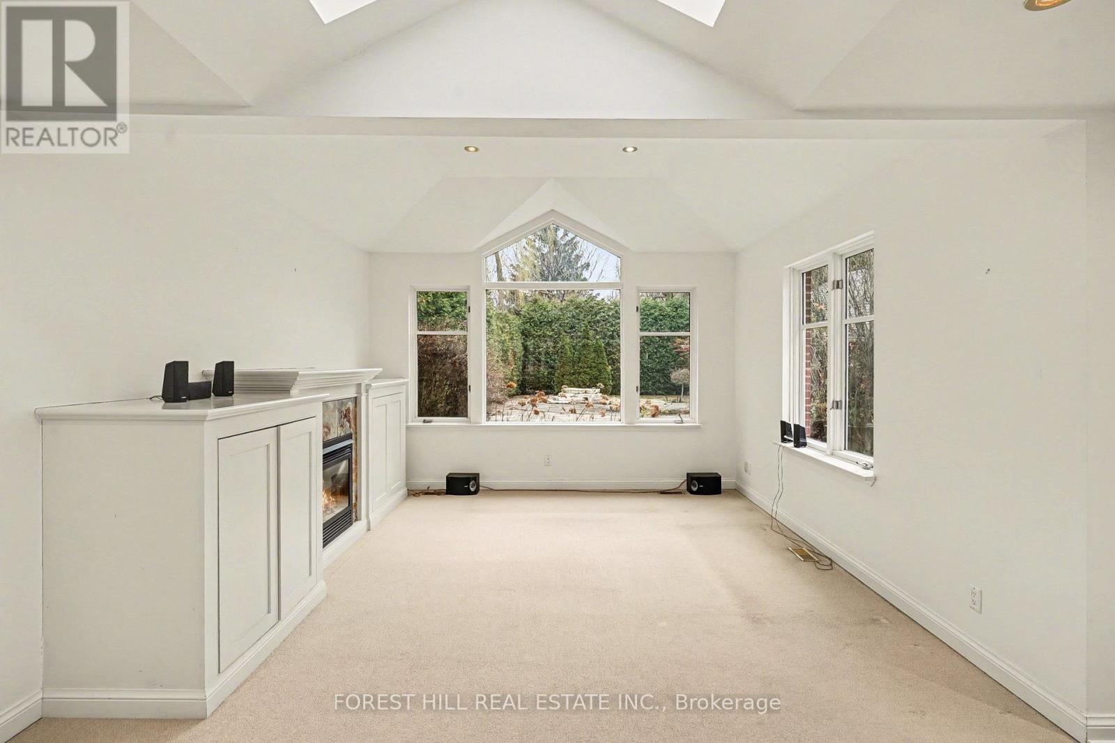 A spacious room with white walls and a large window overlooking a garden.