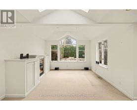 A spacious room with white walls and a large window overlooking a garden.
