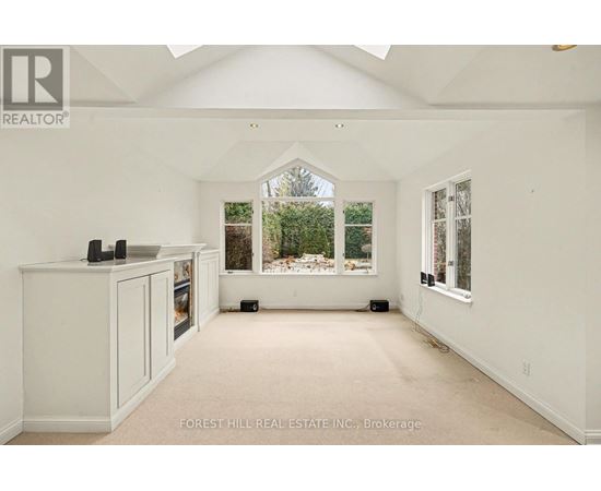 A spacious room with white walls and a large window overlooking a garden.