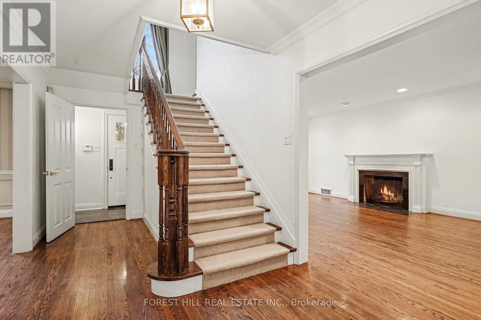 A large, open living room with a fireplace and a staircase with a wooden handrail.