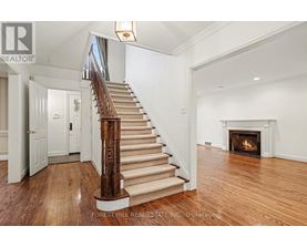 A large, open living room with a fireplace and a staircase with a wooden handrail.