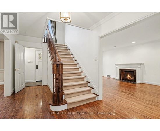 A large, open living room with a fireplace and a staircase with a wooden handrail.